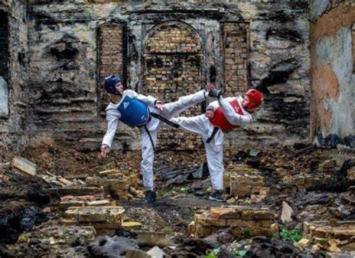 Two taekwondoin fighting each other in ruins.
